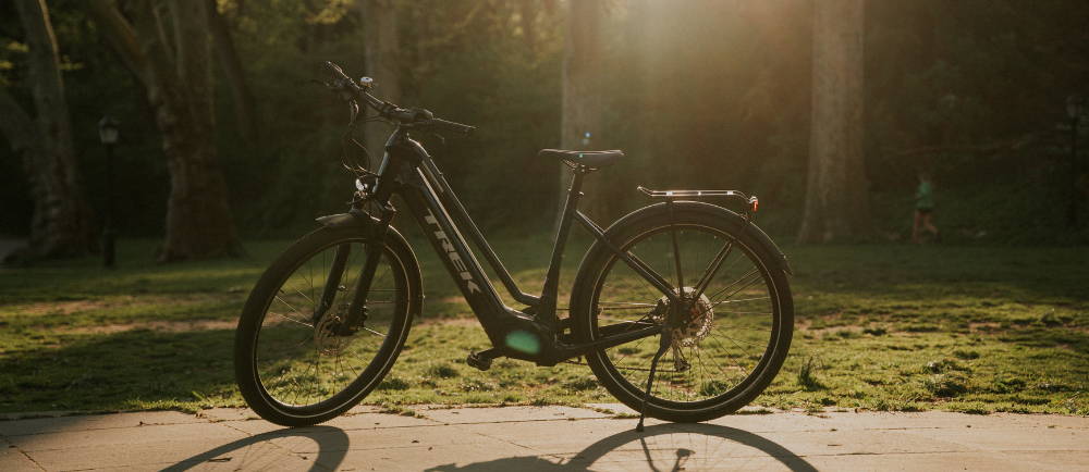 a trek allant electric city bike on a bike path with grass behind it