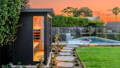 Backyard sauna with garden spike lighting illuminating pathway stepping stones and landscaping near the pool.