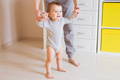 Baby learning to walk while parent holds hands, early walking stage and balance development