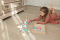 A little girl lying on her room floor and playing with a colorful wooden Montessori toy.