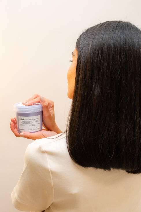 back of woman with sleek black hair holding Davines Love Smoothing Instant Mask
