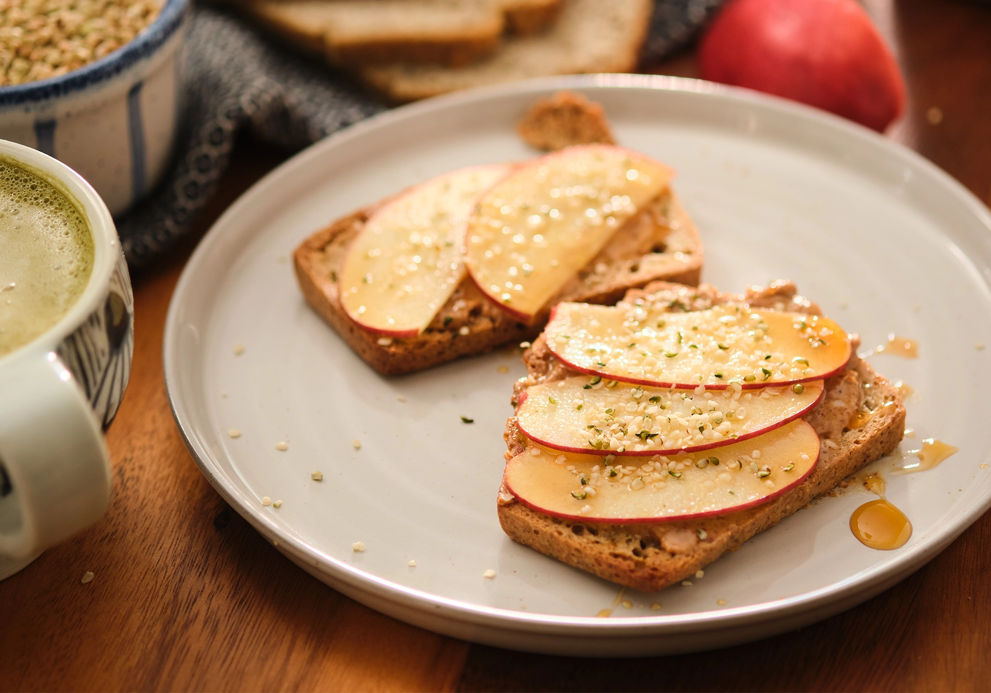 Slices of PACHA Hemp Bread topped with fresh apple slices and served on a plate.