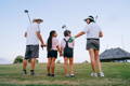 Family holding hands while playing golf on green course