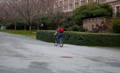 Etudiant avec son sac à dos sur un vélo, roulant sur un campus universitaire