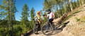 Two mountain bike riders stopped on trail fist bumping
