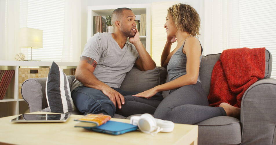 couple sitting on Sofa talking about how snoring is effecting their relationship