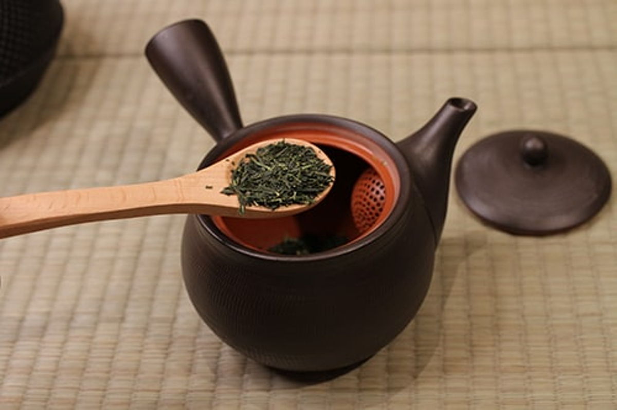Pour cooled water from cups into kyusu over tea leaves