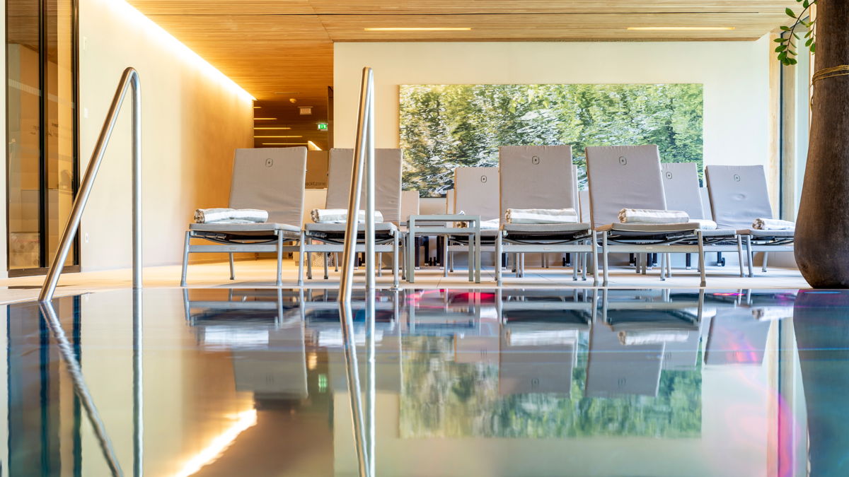 Golf mit Wellness in Ihrem Urlaub verbinden: Pool mit grauen Liegen dahinter