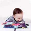 Excited baby laying next to the Montessori Baby Soft Book.