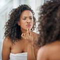 Woman looking into mirror and checking for breakouts.