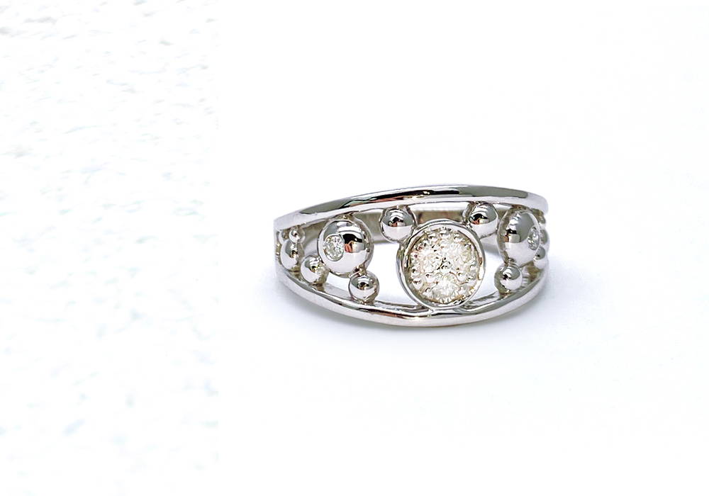 White gold ring with a round diamond in a closed setting in an airy ring body filled with small bubbles