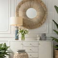 Image is a seagrass mirror and an ivory chest of drawers. 