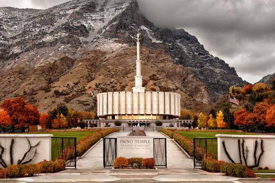 Provo Utah Temple against the mountains surrounded by autumn trees.