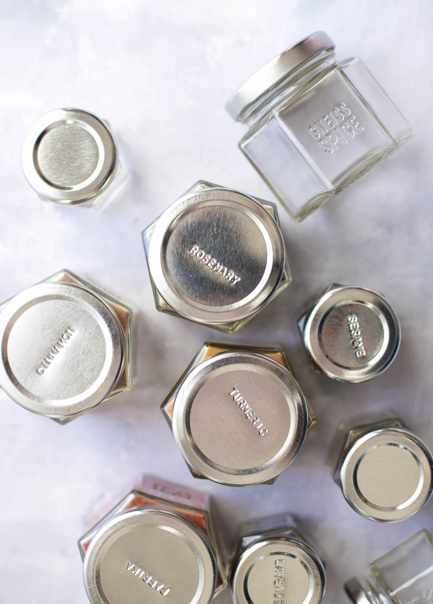 A group of empty clear glass spice jars labeled with the spice name