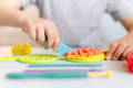 Child slicing a pretend play waffle made out of playdough.