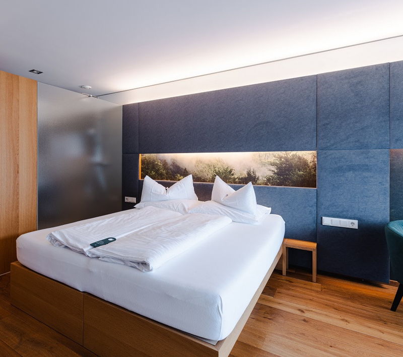 Zimmer mit Bett und 2 Stühlen vor grauer Wand