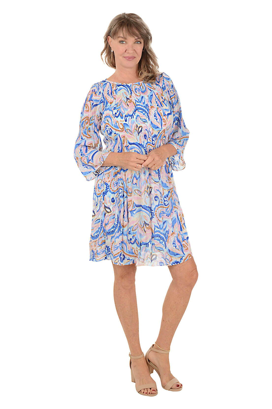 A woman wears a pastel printed dress against a white background