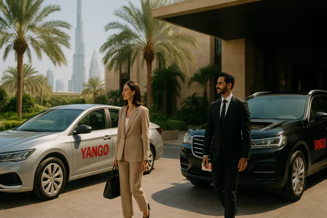 A businessman and businesswoman walk past silver and black Yango cars outside a modern building with palm trees and Dubai skyscrapers in the background.