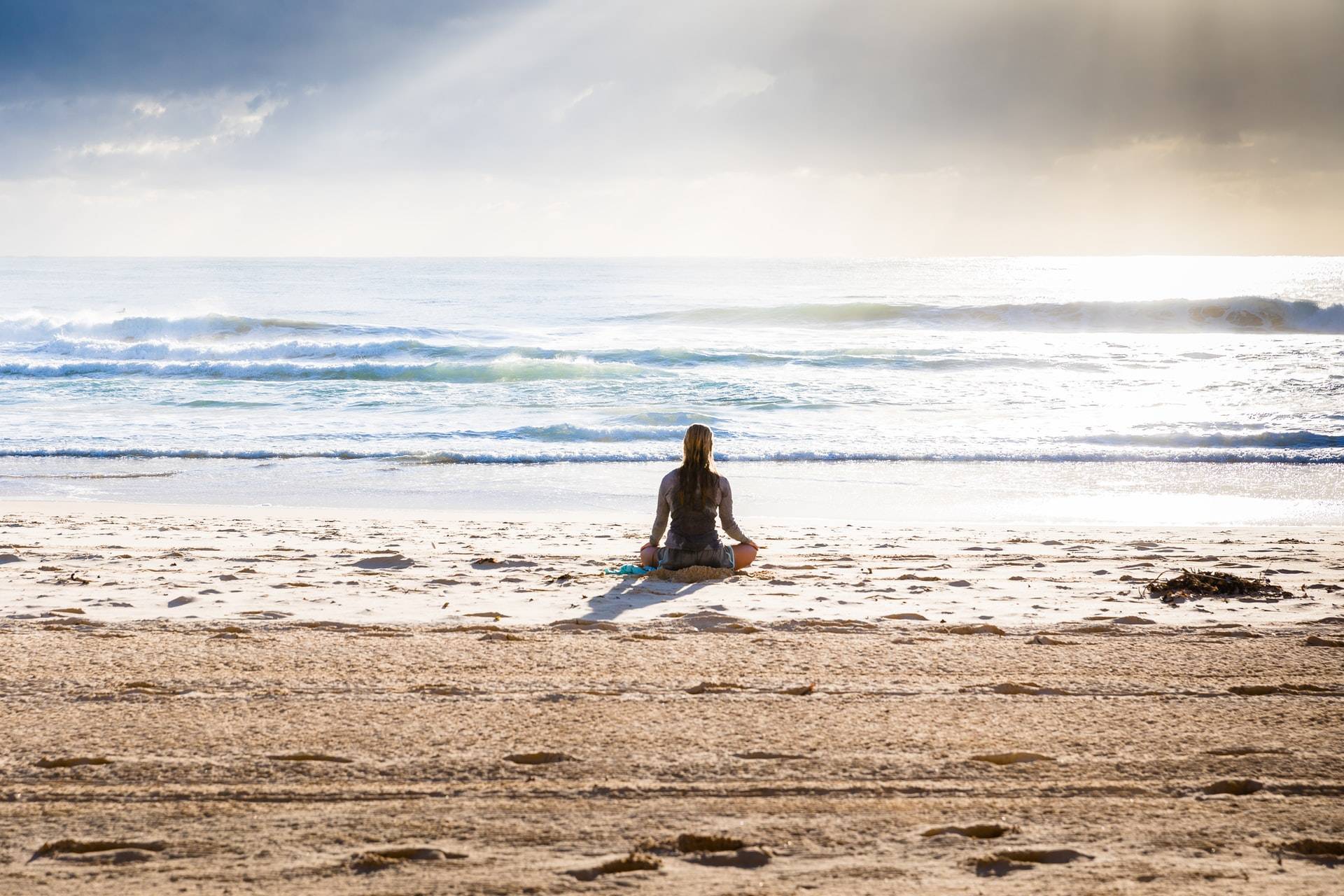 woman sitting in lotus position facing the sea
