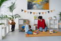 Mother and her kids playing with toys in the playroom. 