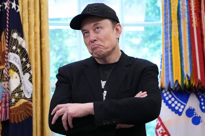 Image may contain: Elon Musk, Baseball Cap, Cap, Clothing, Hat, Face, Head, Person, Photography, Portrait, Adult, and Coat