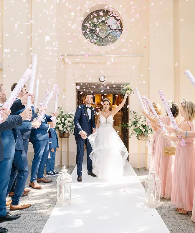 Les mariés sortant de l’église, accueillis par leurs invités lançant des confettis