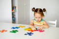 Two year old girl playing with coloful puzzles.