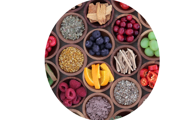 Assorted fresh fruits, herbs, and natural ingredients displayed in wooden bowls on a wooden surface.