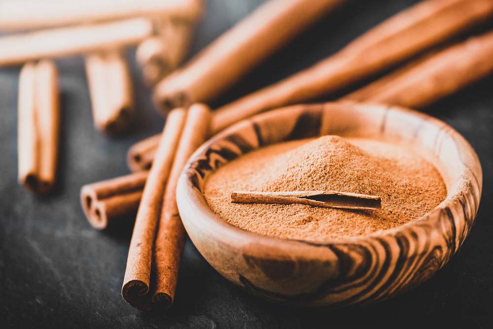 Cinnamon sticks and powder in wooden bowl