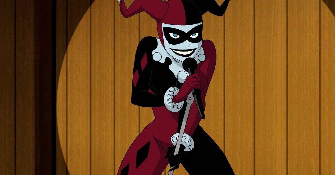 Harley Quinn wearing her villain outfit, in front of an audience with a microphone in her hand.