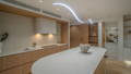 Kitchen Havit custom sinuous LED strip ceiling installation above stone kitchen island with timber cabinetry, downlights and under-cabinet lighting, Manly QLD