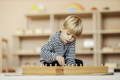 Toddler concentrating on a Montessori-style peg board activity, practicing fine motor skills, hand-eye coordination.