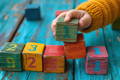 Close up on child's hand stacking colorful wooden blocks with numbers.
