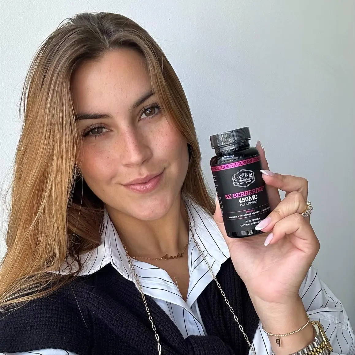 A smiling woman holding a berberine bottle