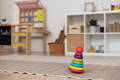 Montessori stacking toy with multicolor rings placed on a carpet in the playroom. 