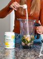 woman adding Revive collagen powder to her smoothie- collagen is tasteless and can mix well with anything!