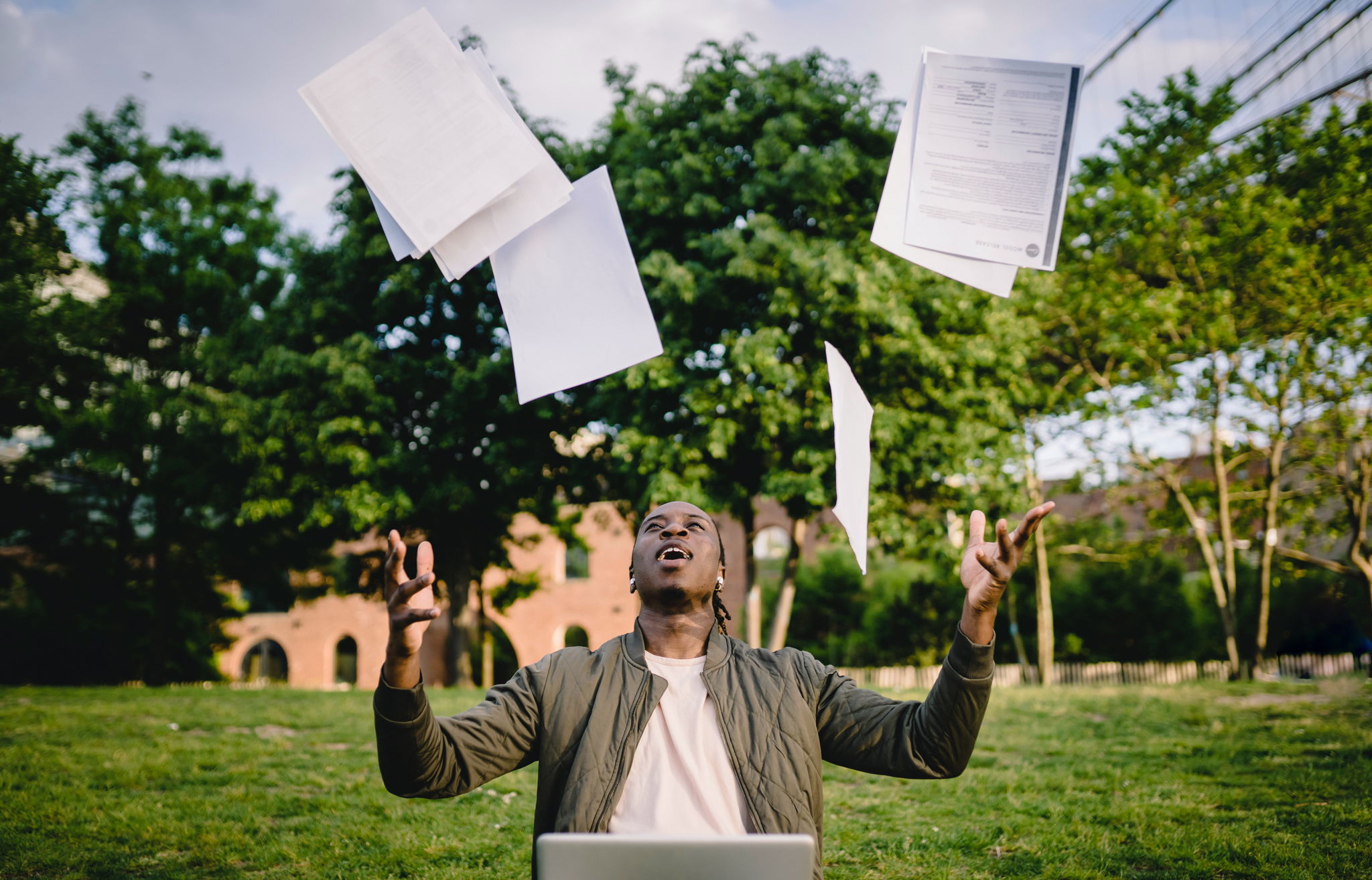 Attractive black man throwing his papers into the air relieved.