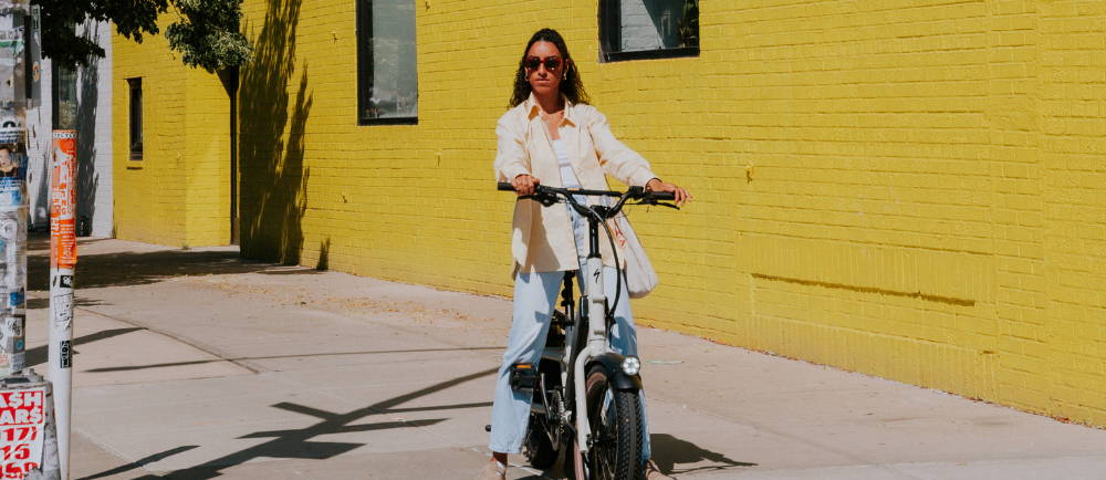 a woman on a specialized globe haul cargo bike in front of a yellow wall