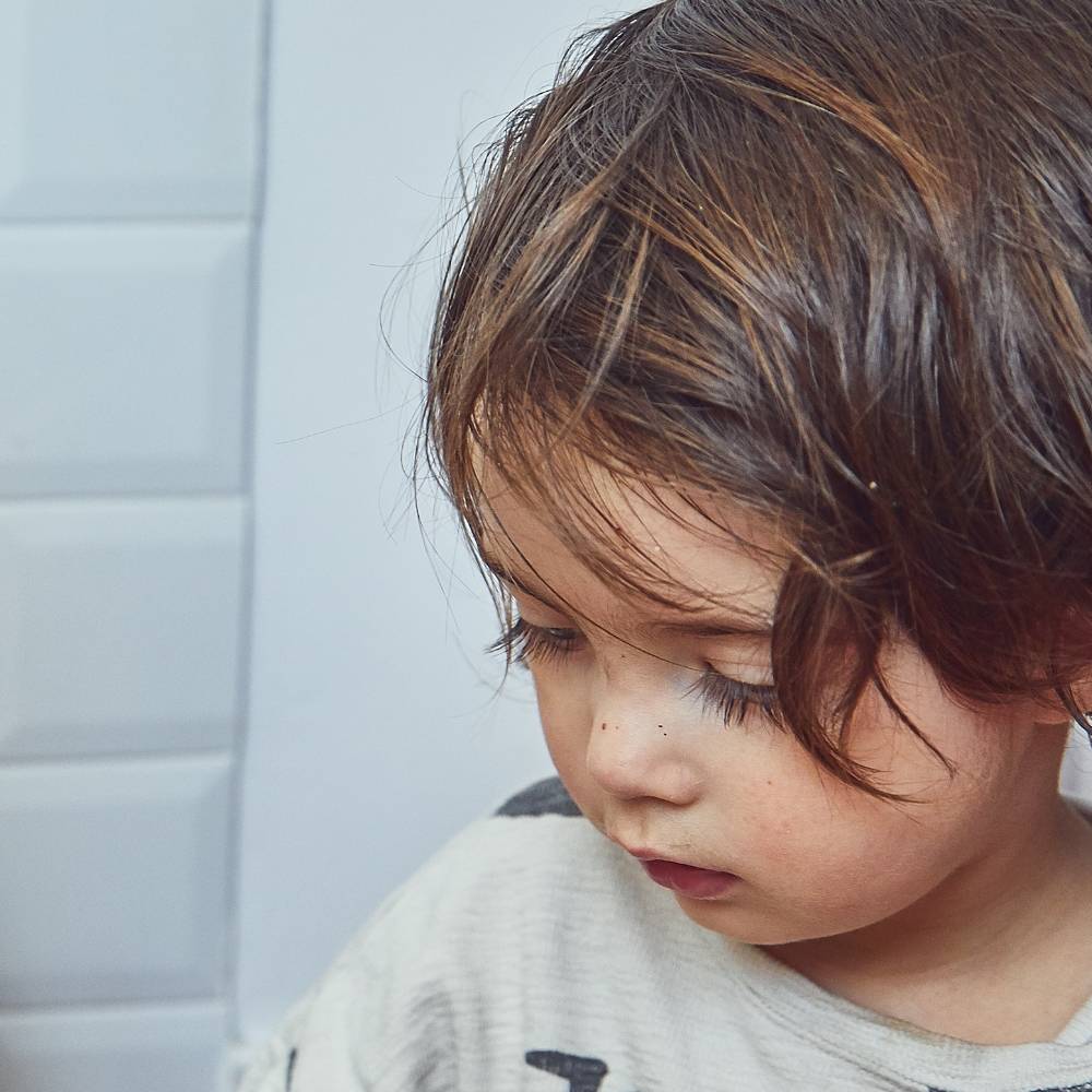 Un petit garçon ayant les cheveux tout lisse après les avoir peigné avec une brosse à cheveux bébé