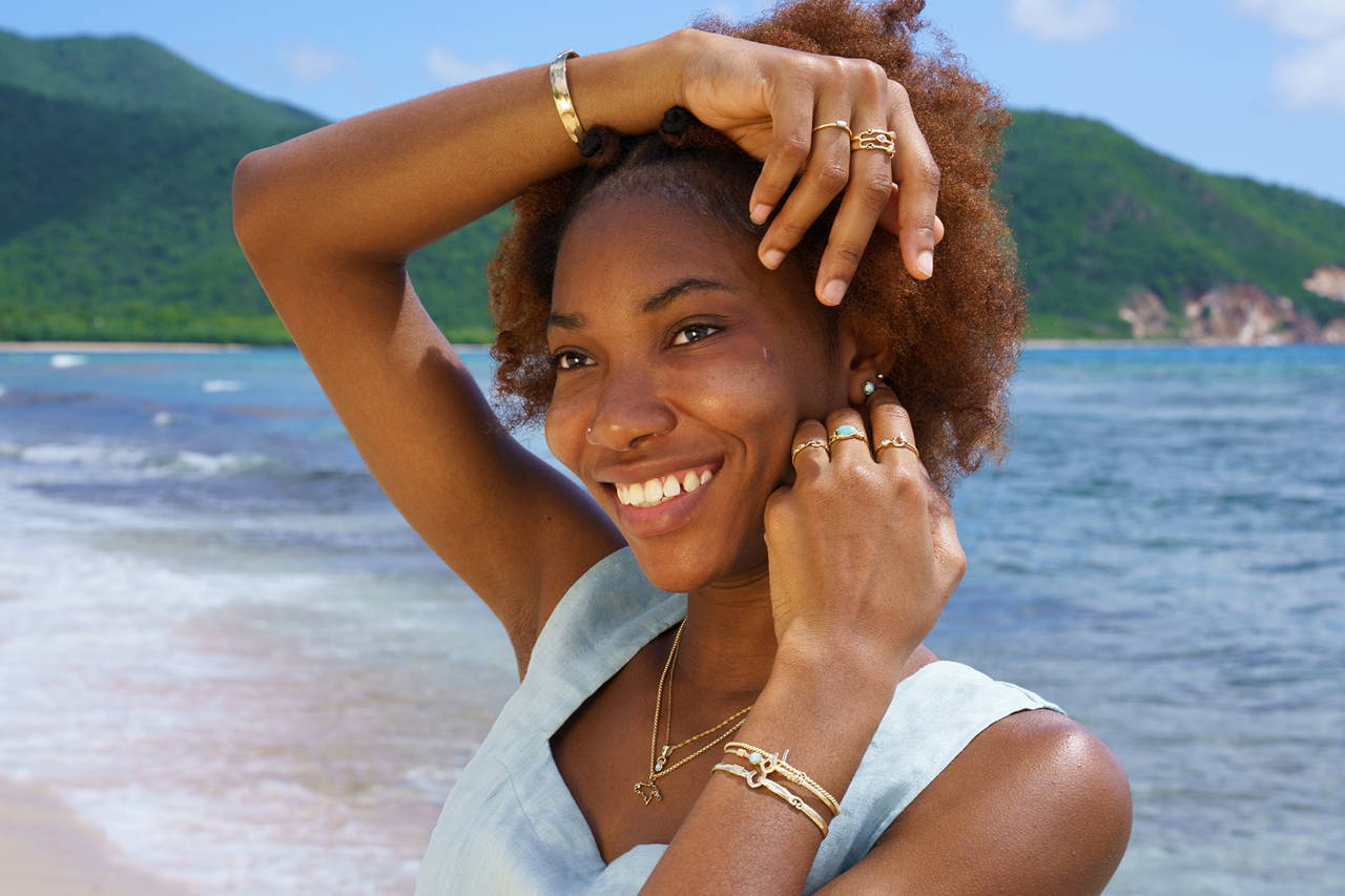 A young woman showing off her jewelry style in front of the ocean on an island