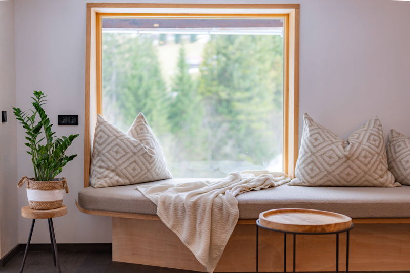 Sitzbank mit Kissen am Fenster im Apartment Vogelfrei von Hugo & Pepi in Mittelberg im Kleinwalsertal.