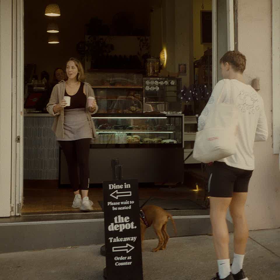 Barista serving two people their coffees 