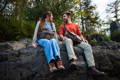 a couple sitting on a rock with trees in the background wearing an jay cooke pack and a tettegouche messenger bag