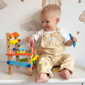 Little boy interacting with the Montessori DIY Fun Chair toy by tightening a screw on it. 