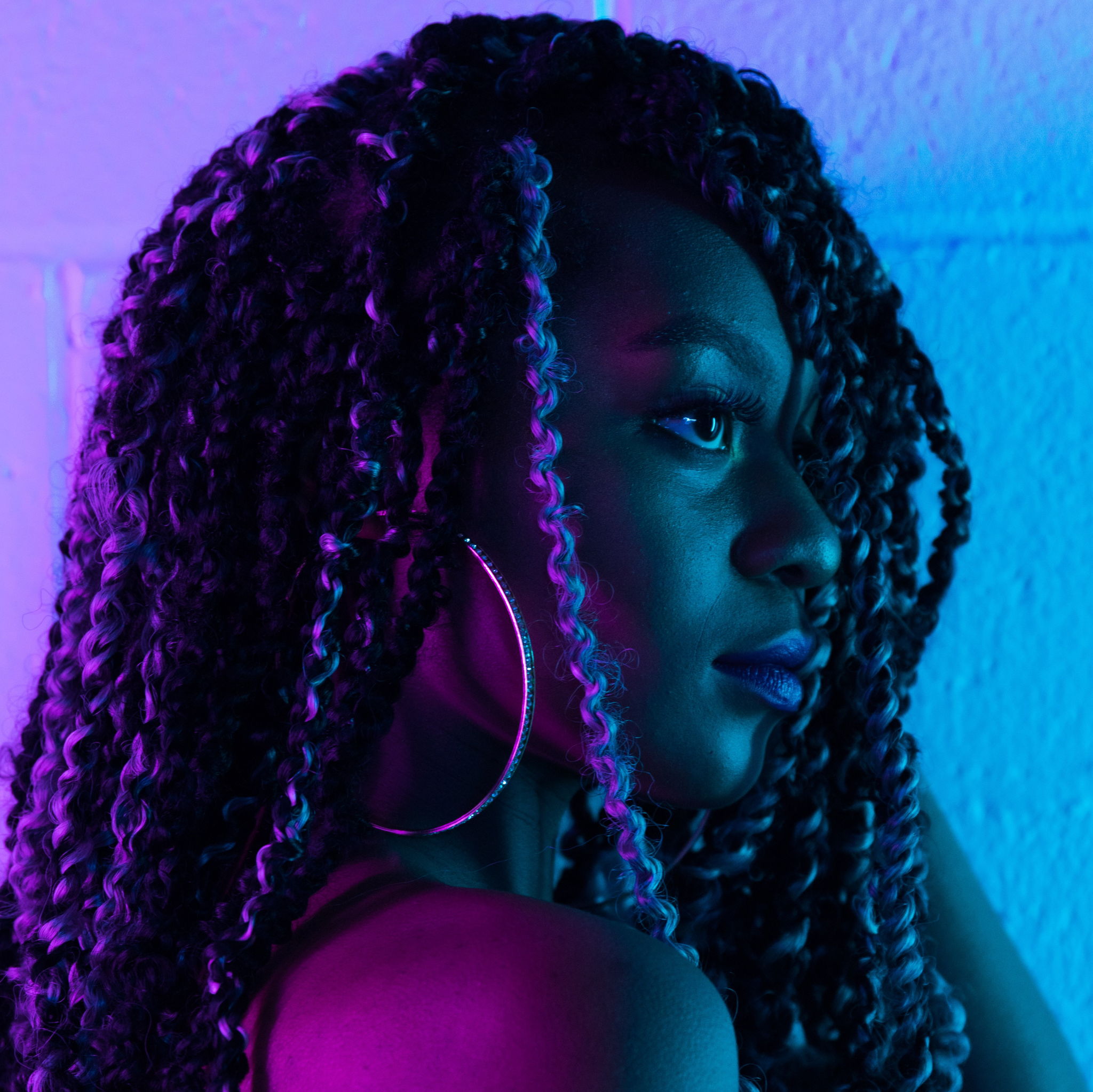 A black woman with long curls surrounded by the bi colors, she is looking forward.