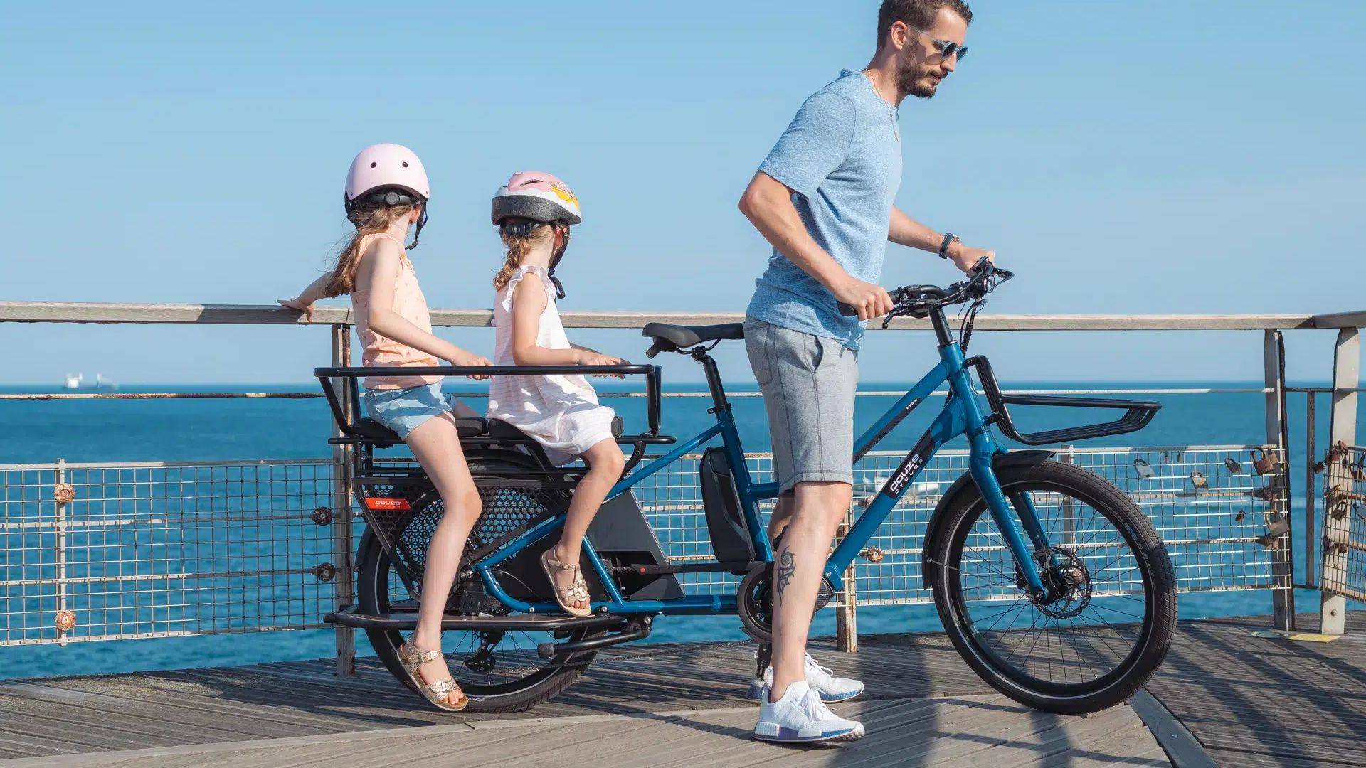 Un papa transporte ses deux enfants grâce à un vélo longtail Douze Cycles