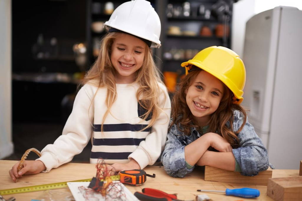 Sisters playing in a workshop and wearing protective helmets.