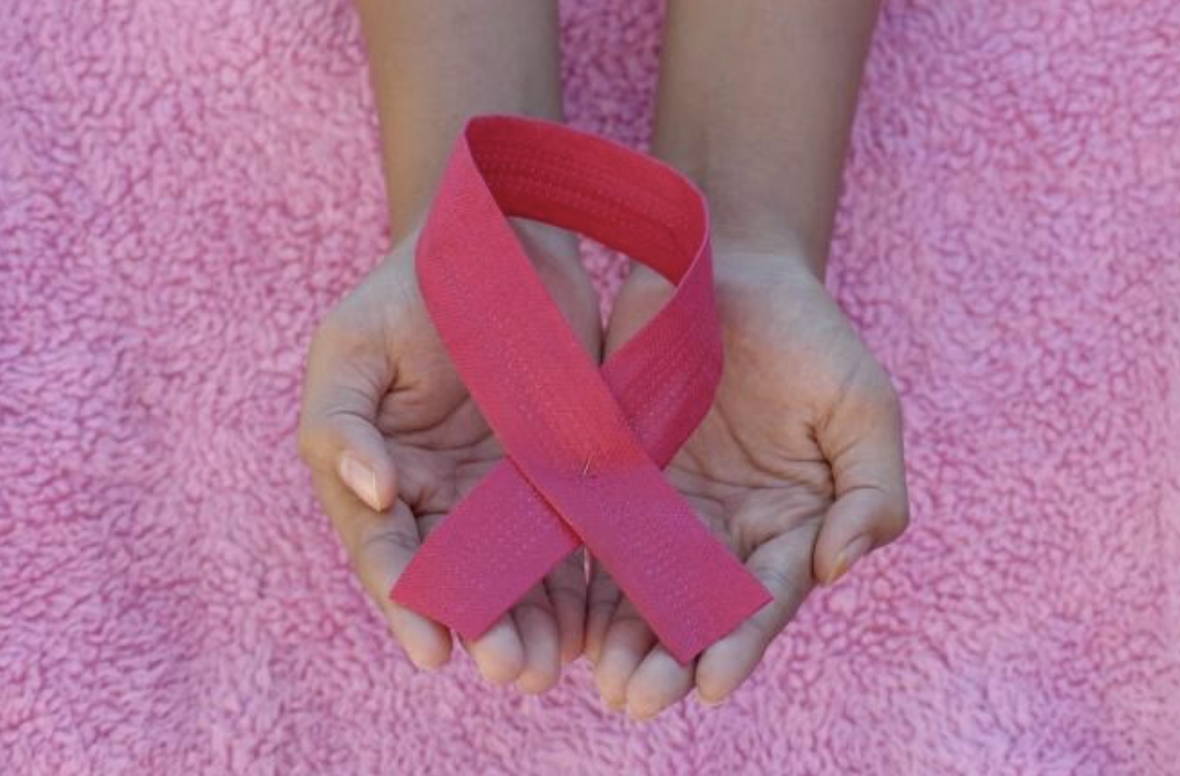 Hands holding pink ribbon: National Breast Cancer Awareness Month