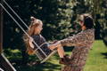 Girl swinging on a traditional swing with mom's help