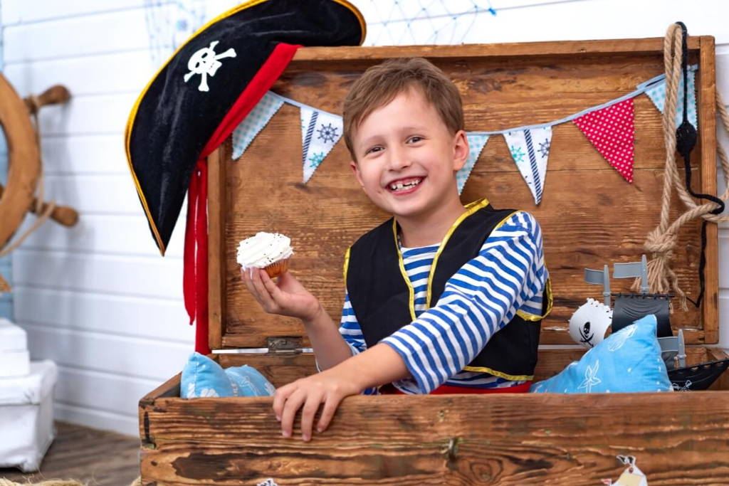 Little boy dressed as a pirate holding a cake.